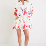 Model wearing a cream mini tiered shirt dress with colourful poppy floral print, puff sleeves and a button front.