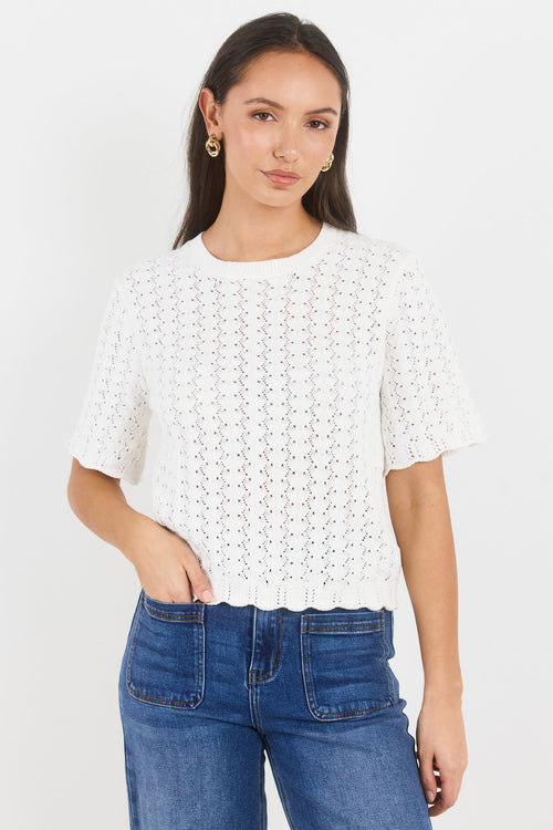 Woman wearing a white lace top and blue jeans on a white background