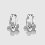 Silver hoop earrings with flower-shaped ends on a light gray background