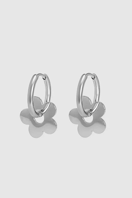 Silver hoop earrings with flower-shaped ends on a light gray background
