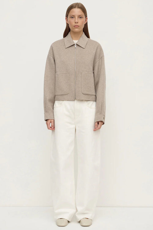 Woman wearing a beige jacket and white pants on a white background
