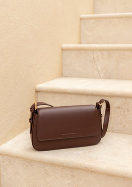 Brown leather handbag on a beige staircase