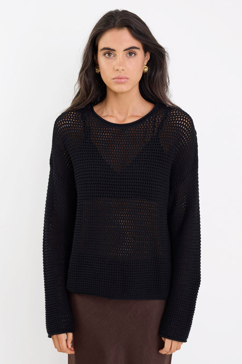 Woman wearing a black textured sweater against a white background
