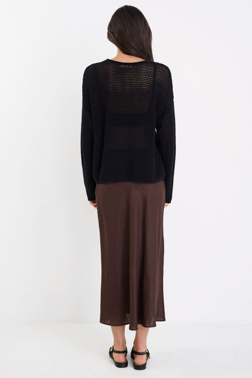 Person wearing a black top and brown skirt on a white background