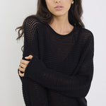 Woman wearing a black knit sweater against a white background
