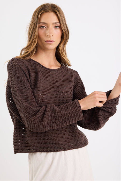 Woman wearing a brown knitted sweater on a white background