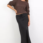 Woman wearing a brown top and black skirt on a white background