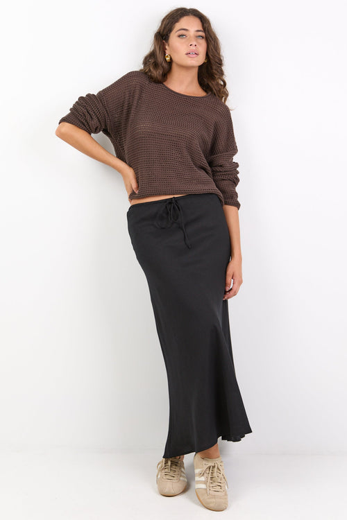 Woman wearing a brown top and black skirt on a white background