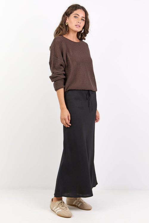 Woman wearing a brown sweater and black pants on a white background