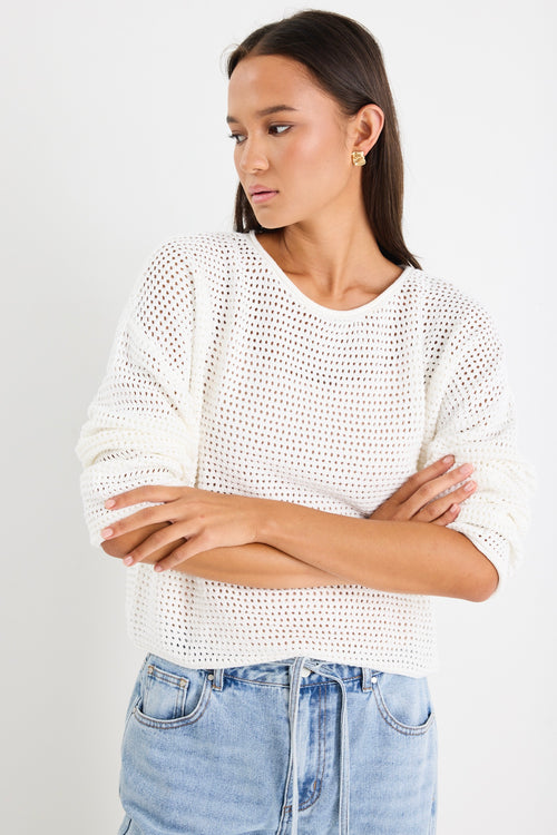 model wears white knit jumper and light blue jeans