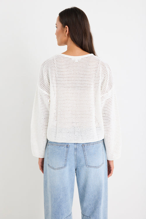 model wears white knit jumper and light blue jeans