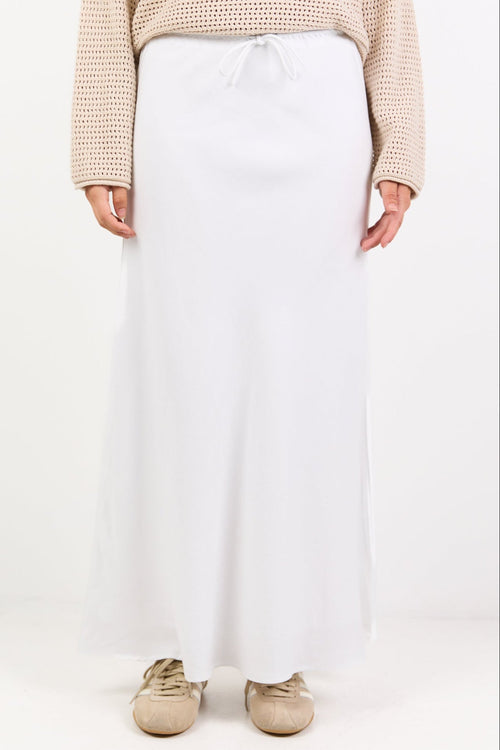 Person wearing a beige sweater and white pants on a white background