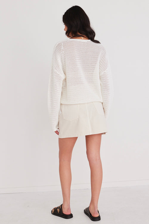 model in white knit crochet jumper and white mini skirt