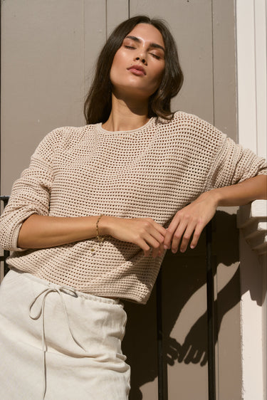 model wears biege knit top