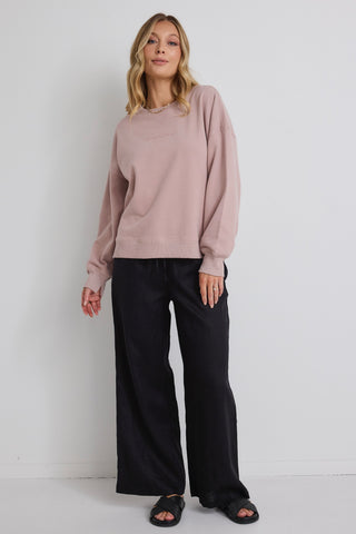 model wears pink jumper and black pants