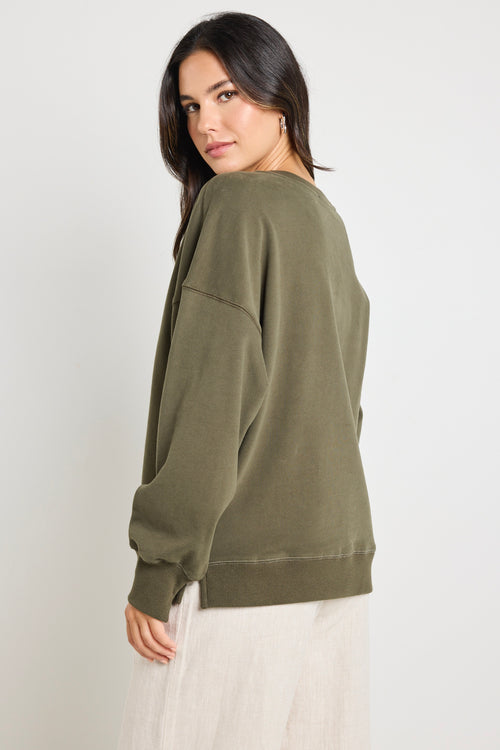 Model wears a khaki green long sleeve sweatshirt 