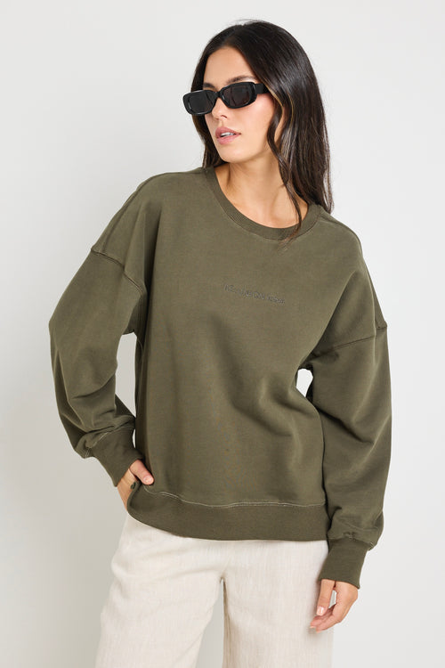 Model wears a khaki green long sleeve sweatshirt 