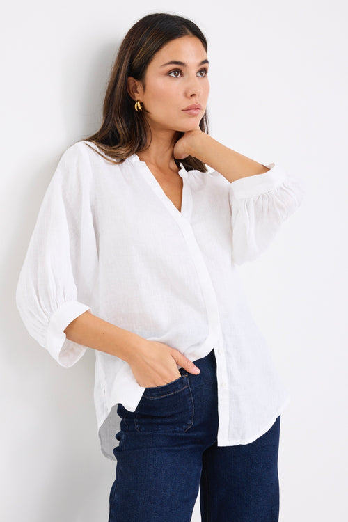 model wears a white linen blouse with dark denim jeans