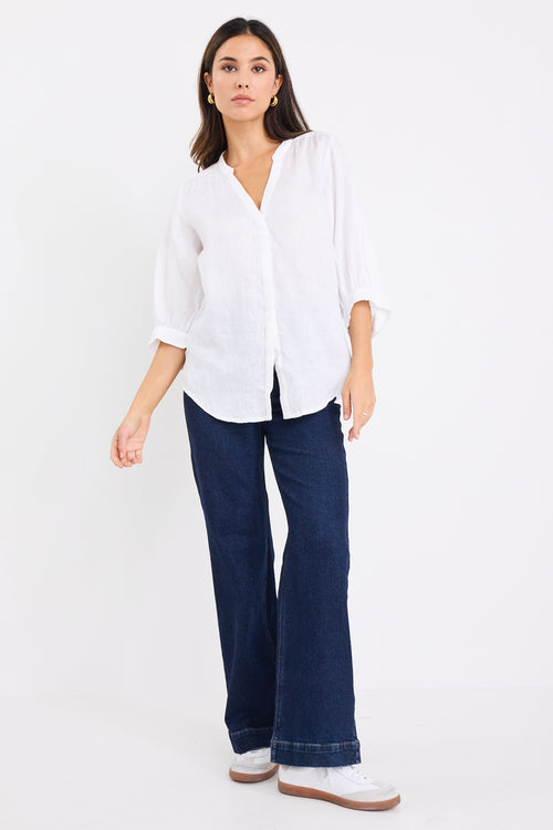 model wears a white linen blouse with dark denim jeans