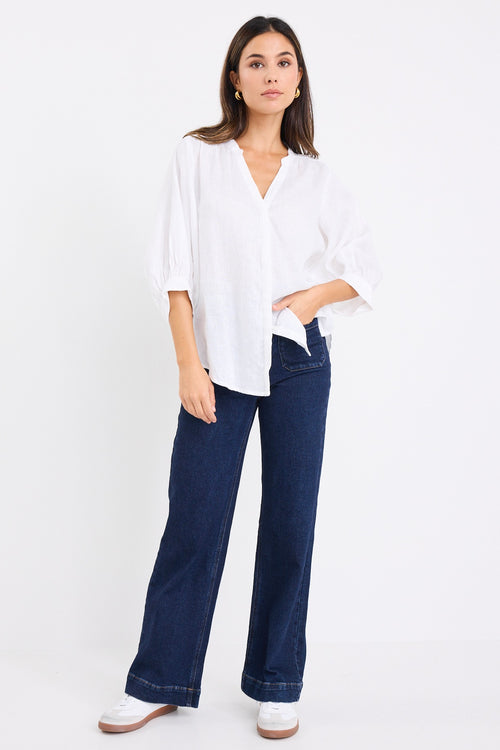 model wears a white linen blouse with dark denim jeans