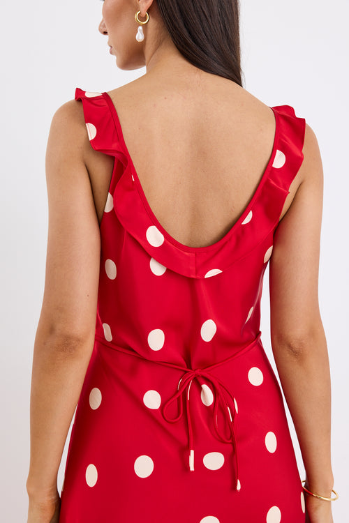 Woman wearing a red satin maxi dress with white polka dots, strappy sleeves, and a flattering bias-cut design.