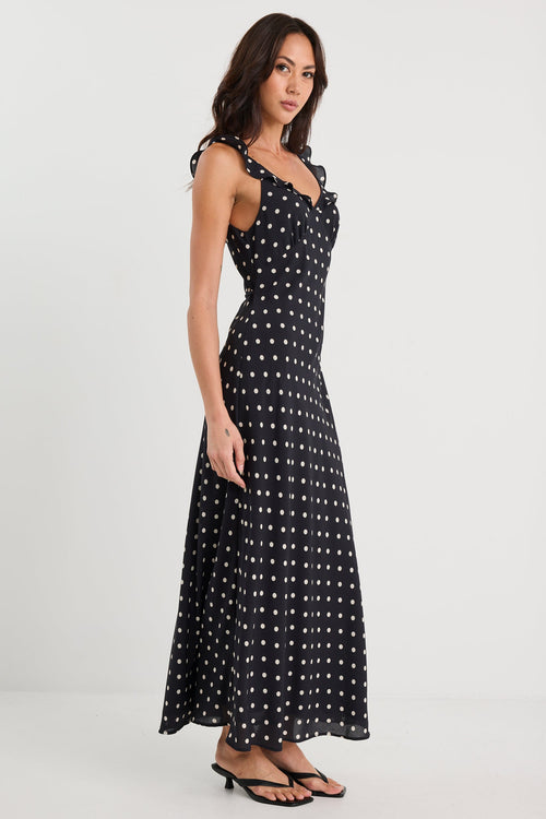 Woman wearing a black dress with white polka dots on a white background