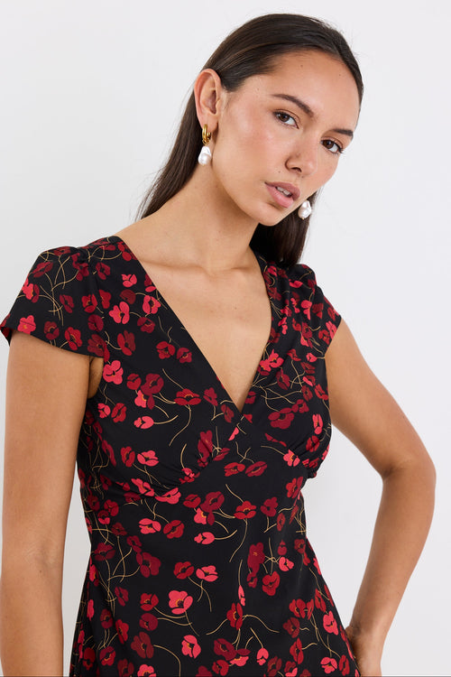 Woman wearing a black dress with red floral pattern against a white background