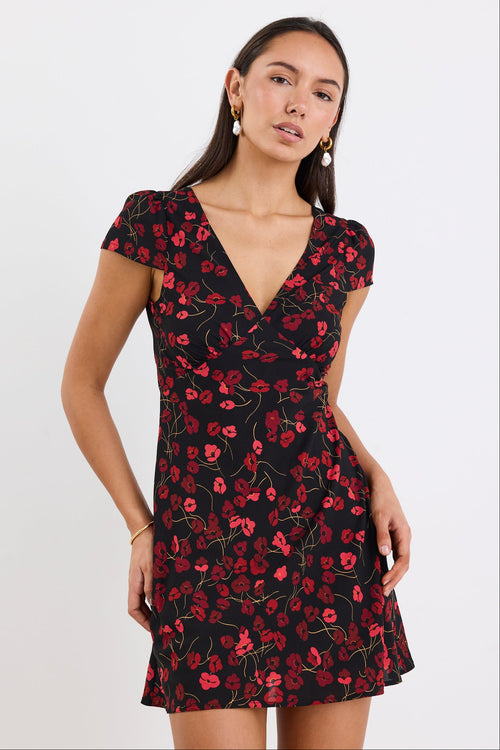 Woman wearing a black dress with red floral pattern on a white background
