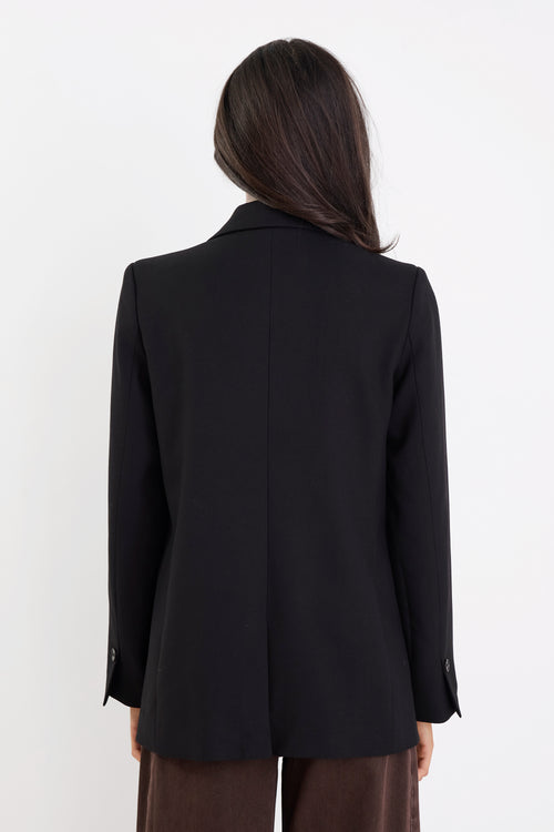 Person wearing a black blazer from behind on a white background