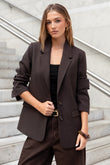 Woman wearing a brown blazer and pants standing on a staircase.