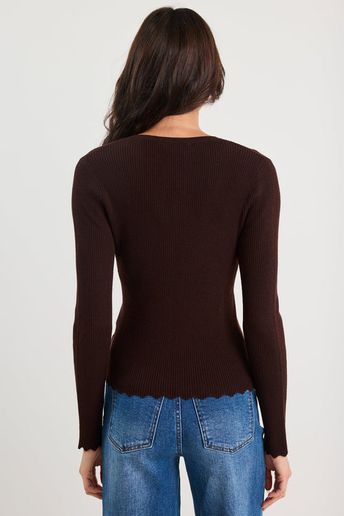 Person wearing a brown sweater and blue jeans on a white background