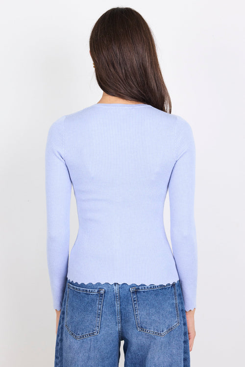 Person wearing a light blue long-sleeve top and blue jeans on a white background