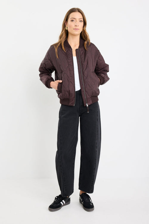 Woman wearing a dark jacket, white shirt, black pants, and black shoes on a white background