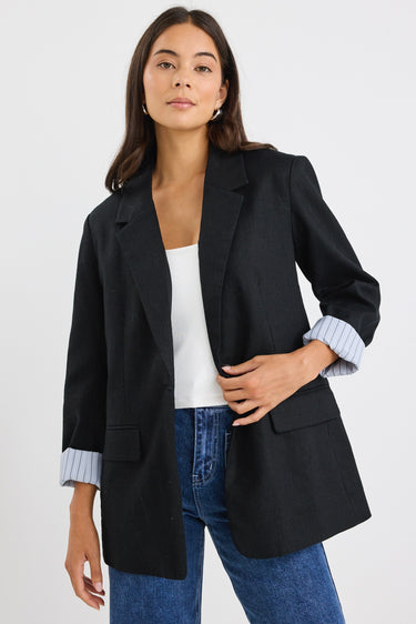 model wears a black linen blazer with blue stripe lining