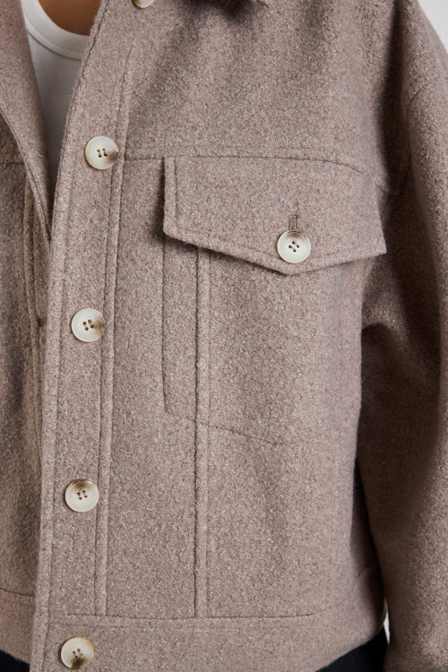 Woman wearing a taupe button-up trucker jacket with chest pockets and long sleeves, styled with a casual white top.
col_pattern