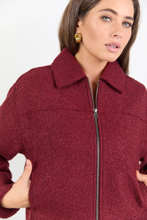 Woman wearing a burgundy jacket with a white background