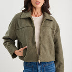 Woman wearing a green jacket and blue jeans on a white background