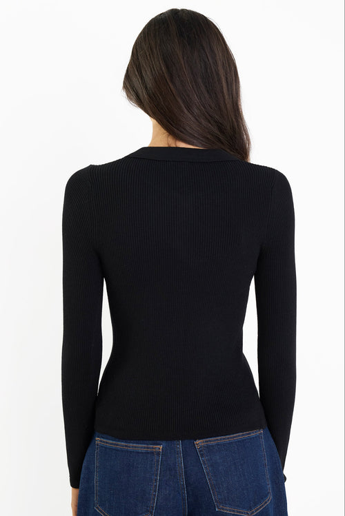 Person wearing a black long-sleeve top and blue jeans on a white background
