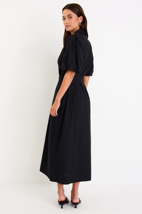 Woman wearing a black dress standing against a white background