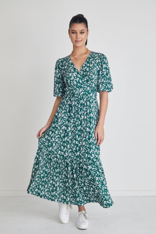 model posing in green floral maxi dress and white sneakers