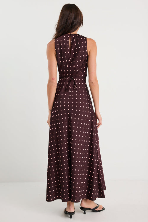Woman wearing a long brown dress with white polka dots on a white background