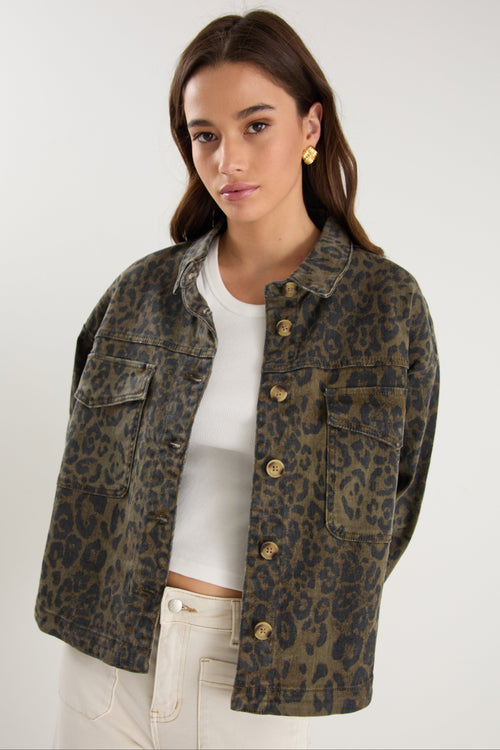 Woman wearing a leopard print jacket over a white top on a plain background