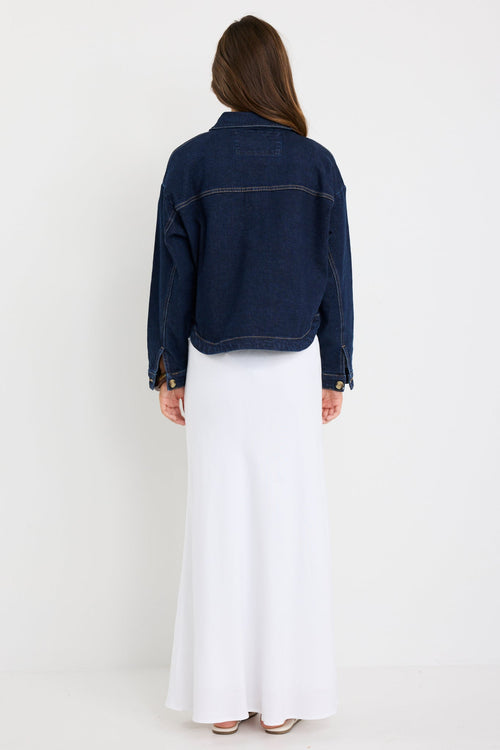 Long sleeve indigo denim jacket with patch pockets, buttoned front, and relaxed fit on model.
