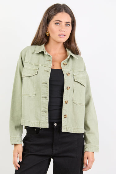 Woman wearing a light green denim jacket on a white background
