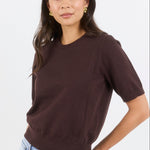 Woman wearing a brown t-shirt and blue jeans on a white background