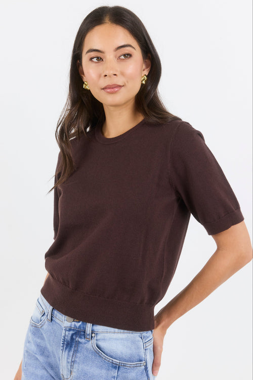 Woman wearing a brown t-shirt and blue jeans on a white background
