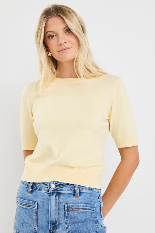 model wears a yellow knit tee with light blue jeans