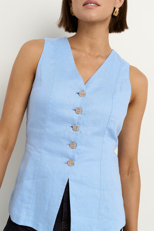 model wears a light blue linen vest with dark blue wide leg jeans
