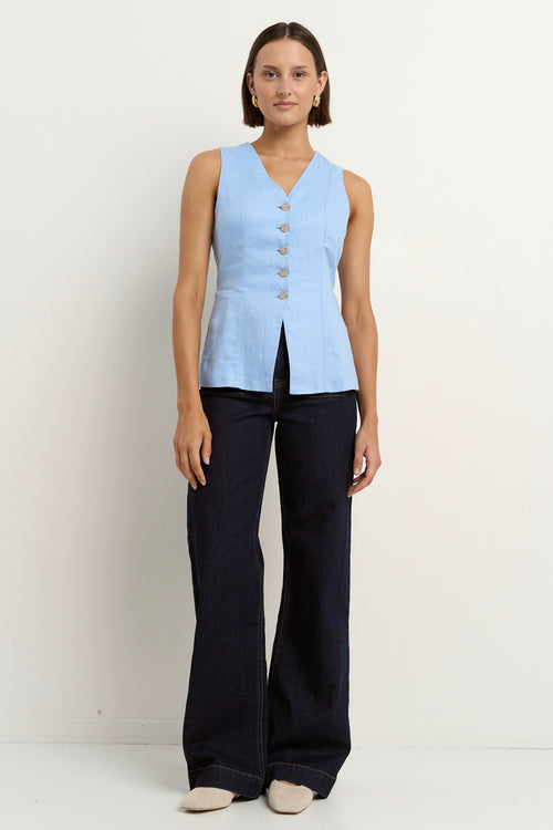 model wears a light blue linen vest with dark blue wide leg jeans