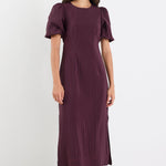 Woman wearing a purple dress with puffed sleeves on a white background